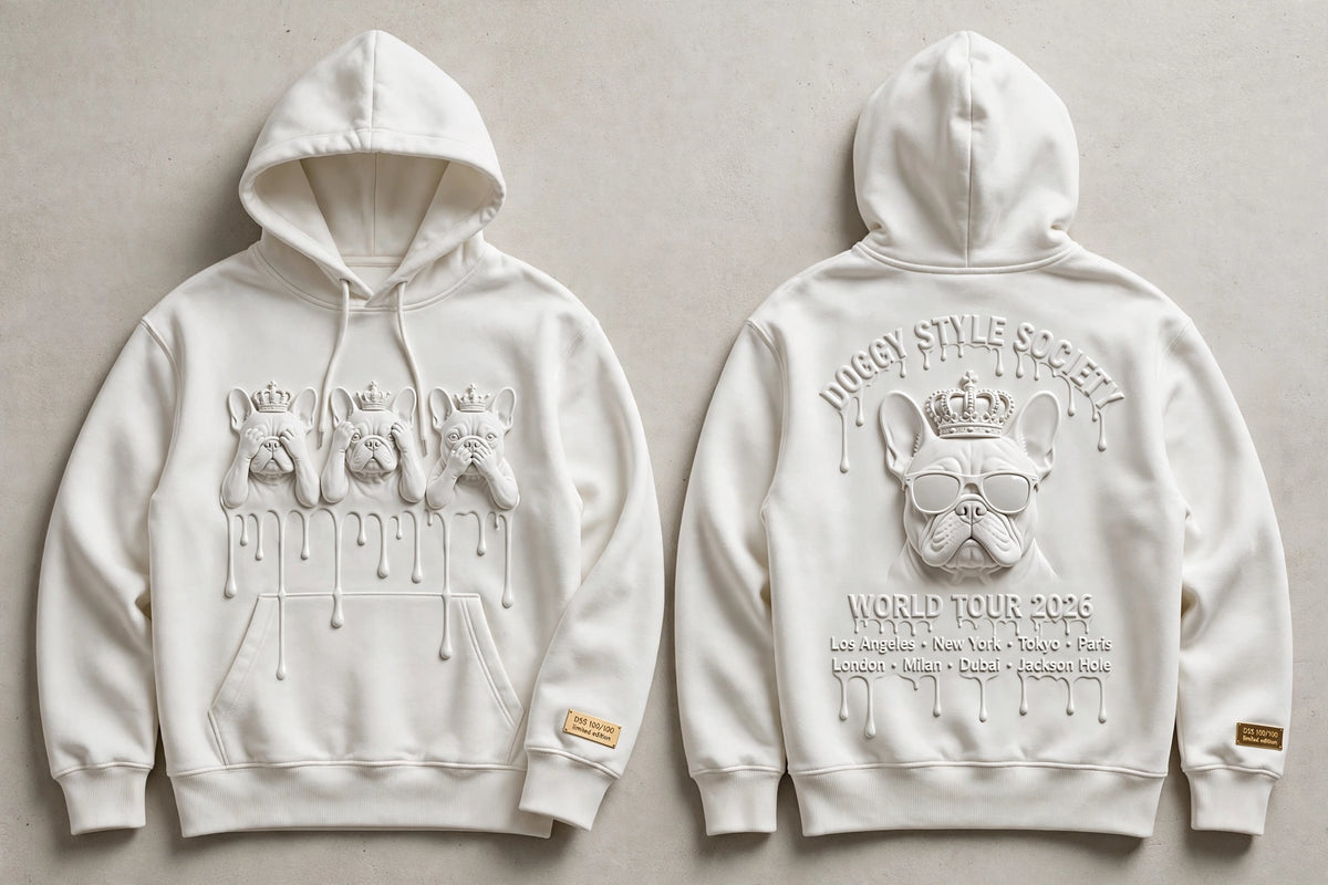 A white pullover hoodie shown from both front and back on a light neutral background. The front features a large embossed graphic of three French bulldogs wearing crowns with dripping paint details.