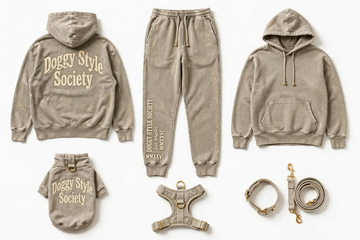 A coordinated dog apparel set laid out on a white background, including a hoodie, sweatpants, a small hoodie, a harness, a collar, and a leash. The pieces are all in a warm taupe/beige tone with cream text branding reading 'Doggy Style Society.