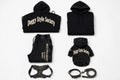 A flat-lay product collection of black apparel and accessories for dogs, including a large hoodie, a small hoodie, matching sweatpants, a harness, and a leash, all featuring the 'Doggy Style Society' logo in beige on a white background.